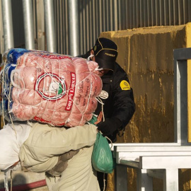 Una mujer porteadora carga con un fardo en el paso habilitado entre Ceuta y Marruecos.- APDHA