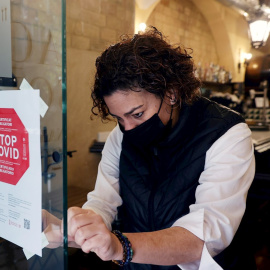 Una empleada de un hotel coloca un cartel a la entrada de su restaurante en València.