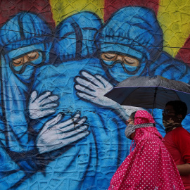 Una mujer y su hijo pasan frente a un graffiti en Mumbai, India.
