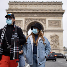 Los peatones con mascarillas caminan por los Campos Elíseos en el centro de París.