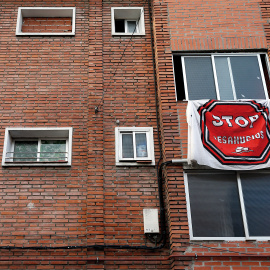 Vanessa sostiene a su hija en la ventana de su cocina en Valladolid el 30 de enero de 2014, mientras miembros de la PAH luchan para evitar el desahuciio.- AFP