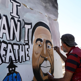 Un hombre sirio última un grafiti en homenaje a George Floyd en las ruinas de una casa en Idlib (Siria)./ EFE/EPA/YEHYA NEMAH