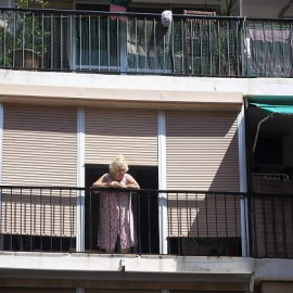 Una mujer sale a la terraza en uno de los barrios confinados / Getty Images