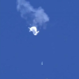 Un pescador graba los restos del globo chino a bordo de una barca de la marina de EEUU