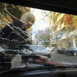 La vida no se para con la guerra. Una mujer limpia en Beirut el parabrisas de su coche que presenta varios impactos de bala. bela szandelsky / ap