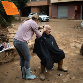Una mujer corta el pelo a un vecino de Paiporta (Valencia), varias semanas después de la dana.