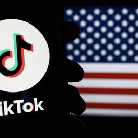 Imagen del logotipo de TikTok en un teléfono inteligente con la bandera de América de fondo.