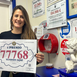 Una mujer muestra el número 77768, premiado con un cuarto premio de la Lotería de Navidad.