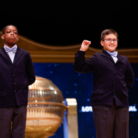 Los niños de la Residencia San Ildefonso de Madrid muestran el número 37.876, un quinto premio dotado con 60.000 euros en cada serie, 6.000 euros al décimo.