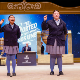 Las niñas de la Residencia San Ildefonso de Madrid Yadira Quinde Mendoza (i) y Kiara Román Benítez (d) muestran el número 45.225, uno de los quintos premios, durante el sorteo de la Lotería de Navidad que se celebra este domingo en el Teatro Real, en Madrid