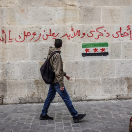 Un hombre camina por una calle de Damasco en Siria. En la pared puede leerse: "Maldito seas para siempre, Assad". Imagen de archivo.