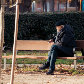 Un hombre anciano sentado en un banco, en Madrid.