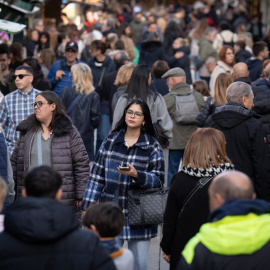 Varias personas observan el ambiente navideño en la Fira de Santa Llúcia de Barcelona, en la plaza de la Catedral, a 5 de diciembre de 2024, en Barcelona.