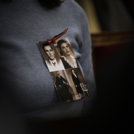 Una mujer con las fotos de unos familiares durante el acto homenaje a víctimas del franquismo, en el Congreso de los Diputados.