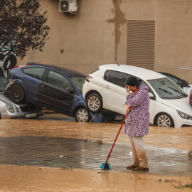 Una mujer junto a vehículos destrozados tras el paso de la DANA por el barrio de La Torre de Valencia.