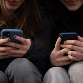 Imagen de archivo de dos jóvenes usando el teléfono móvil.