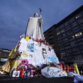 Flores, mensajes y velas se colocan al pie de una estatua de Juan Pablo II a la entrada del hospital Gemelli, donde el Papa Francisco aún se encuentra internado, en Roma, Italia.