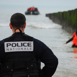 Un policía francés observa a un migrante que se acerca a la orilla después de intentar cruzar el Canal de la Mancha para llegar a Reino Unido.