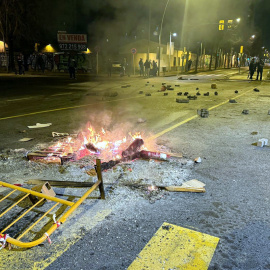 El passeig dels Països Catalans de Salt amb pedres a la calçada i una foguera fumejant arran dels aldarulls.