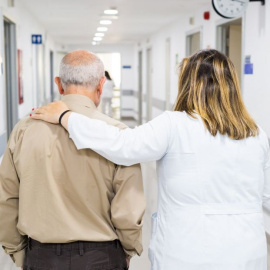 Una sanitaria acompaña a un paciente mayor en un centro sanitario