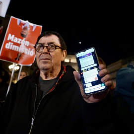 Imagen de archivo de un hombre muestra la alerta en su móvil durante una manifestación en contra de Mazón, a 29 de noviembre de 2024, en València.