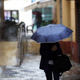 Una persona se protege de la lluvia en Málaga el 13 de marzo de 2025.