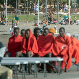 Imagen de archivo de un grupo de migrantes en Tenerife, con varios turistas al fondo.