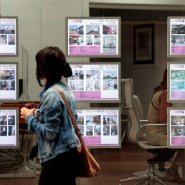 Imagen de archivo de una joven frente a una inmobiliaria.