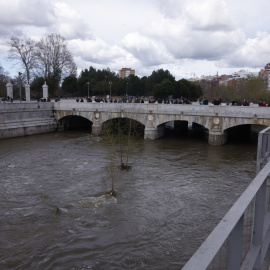 Varias personas observan el caudal del río Manzanares a su paso por Madrid, a 23 de marzo de 2025.
