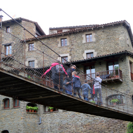Una família de turistes travessa el pont penjant de Rupit