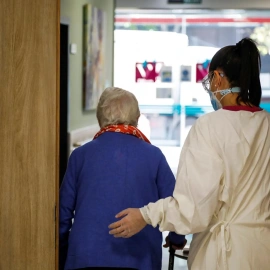 Una persona mayor entra en rehabilitación acompañada por una sanitaria