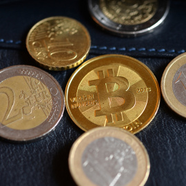 Monedas de euro junto a una representación de Bitcoin.