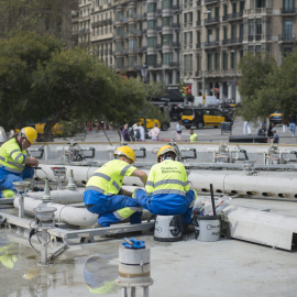 Una de les fonts de plaça Catalunya amb tècnics revisant la instal·lació