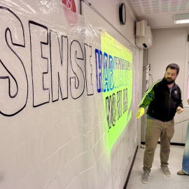 Dos docents preparen una pancarta de suport a les famílies desallotjades del carrer Justícia de Rubí.
