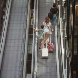 Varias personas con maletas en las escaleras mecánicas de la terminal T4 del Aeropuerto Adolfo Suárez Madrid-Barajas, a 12 de julio de 2024, en Madrid (España).