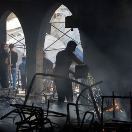 Un hombre apaga un incendio en una escuela que acoge a personas desplazadas tras un ataque israelí en la ciudad de Gaza, este 23 de abril de 2025.