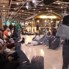 Passatgers amb ordinadors, telèfons mòbils o estirats per descansar a l’estació de Sants de Barcelona, aquest dilluns a la nit després de l'apagada general