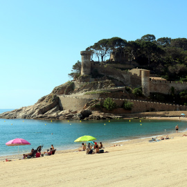 Alguns banyistes a la platja de Tossa de Mar amb la Vila Vella al fons en una imatge d'arxiu