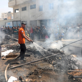 Palestinos rocían agua en puntos conflictivos mientras limpian los residuos de tiendas de campaña destruidas en un ataque israelí en la ciudad de Gaza.