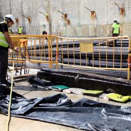 Un treballador remulla amb aigua la quilla trobada per mantenir-ne l'estat de conservació