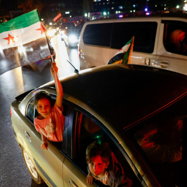 Una niña sostiene una bandera siria, mientras la gente celebra en Damasco el anuncio del presidente de EEUU, Donald Trump, del levantamiento de las sanciones a Siria.