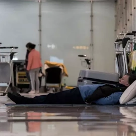 Una persona tumbada en el suelo en la T4 del Aeropuerto Adolfo Suárez Madrid-Barajas, a 12 de mayo de 2025.