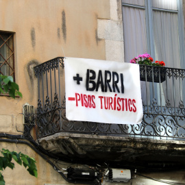 Pla detall d'un cartell reclamant menys pisos turístics al Barri Vell de Girona