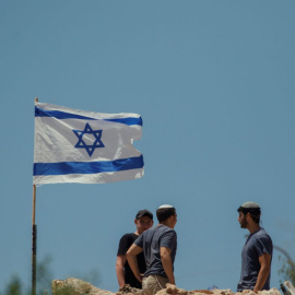 Colonos judíos izan banderas israelíes en viviendas palestinas en la aldea de Bruqin, en el norte de Cisjordania, a 23 de mayo de 2025. (Foto de