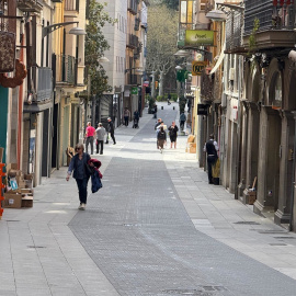 Diverses persones passegen per un carrer del nucli antic d'Olot