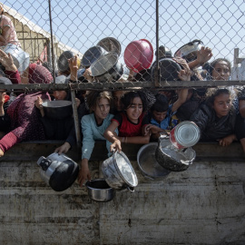 Palestinos desplazados se agolpan frente a un comedor social para recibir raciones limitadas ante la escasez de alimentos, en Jan Junis, en el sur de la Franja de Gaza, este viernes.