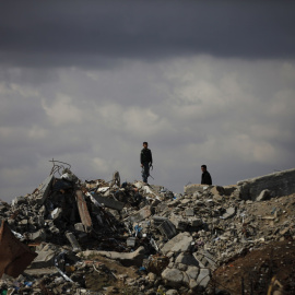 Palestinos desplazados caminan sobre los escombros de los edificios derrumbados en el campamento de Al-Bureij.