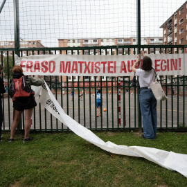Varias personas ponen una pancarta antes de una concentración para denunciar el asesinato de una niña de 13 años por su padre en Rekalde, Bilbao.