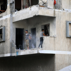 Palestinos inspeccionan los escombros después de que un israelí atacara una casa, en la ciudad de Gaza.