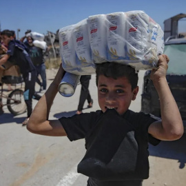 Fotografía de archivo de palestinos cargando suministros entregados por GHF en la Franja de Gaza.